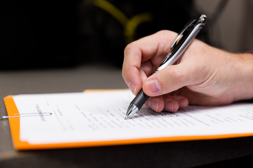 Hand of doctor writing a referral to see a sports medicine provider.