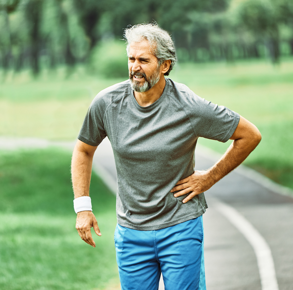 Older gentleman walking, holding his hip in pain, and wondering "do I need Orthopedic doctor in Kansas City?"