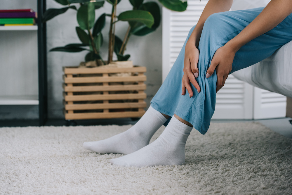 Woman holding leg in pain from tingling and numbness
