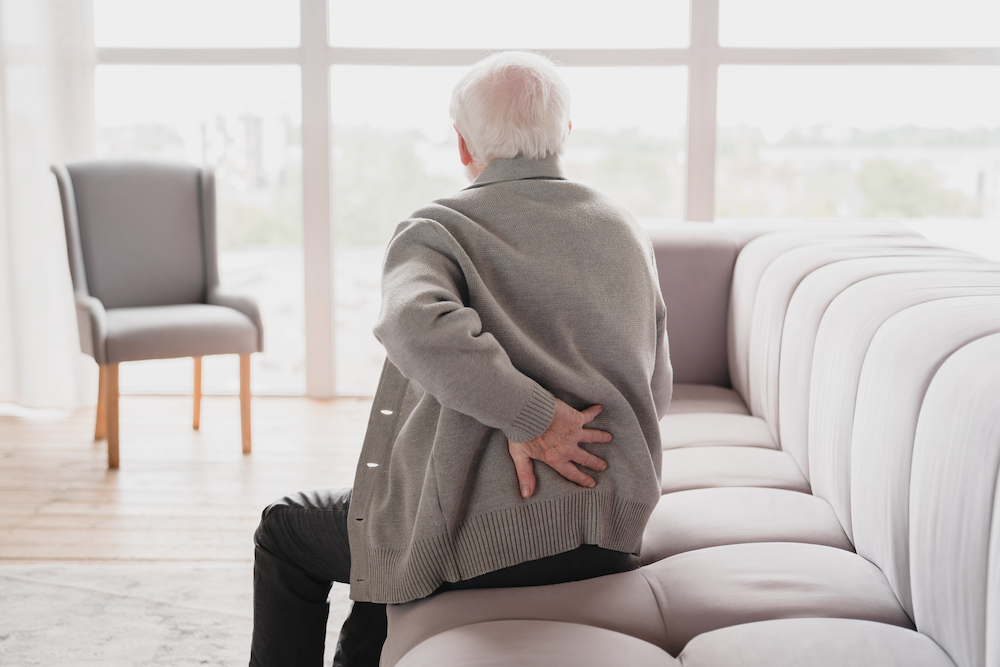 Older man holding his back in pain, needing a lumbar radiculopathy treatment in Kansas City