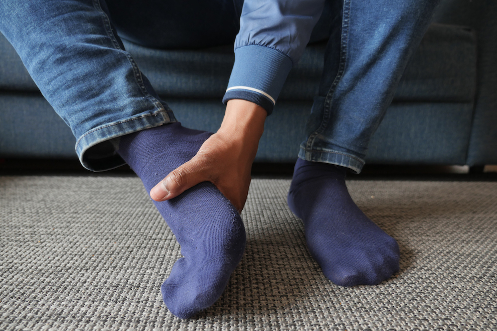 Person holding his foot and needing plantar fasciitis treatment in Kansas City